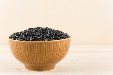 Fototapeta na wymiar black beans on wood background
