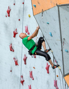 Aged Person Practicing Extreme Sport Elderly Male Climber Makes Hard Move and Looking High Up on Outdoor Climbing Wall Sport Competitions