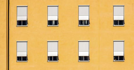 Obraz premium Wall in yellow colors with windows and shutters in high contrast