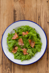 salad with smoked salmon on plate on brown wooden background