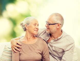 happy senior couple hugging on sofa at home