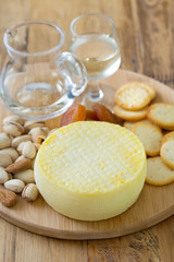 cheese with cookies, nuts and wine on tray on brown background