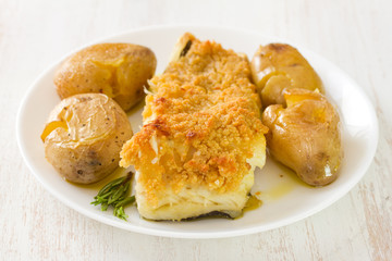 fried fish with potato and oil on dish on white background