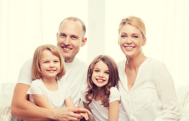 smiling parents and two little girls at home