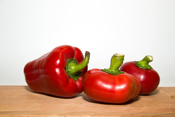 Three ripe red peppers on over white