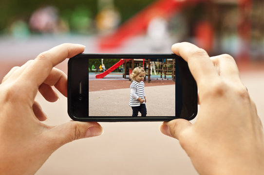 Woman taking a photo of baby girl with smartphone