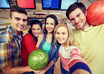 happy friends taking selfie in bowling club