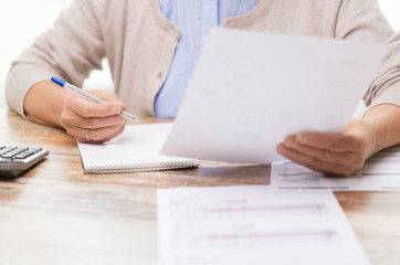 senior woman with papers and calculator at home