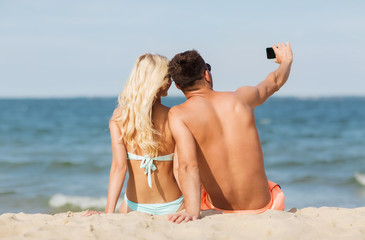 happy couple in swimwear sitting on summer beach