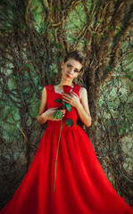 Beautiful woman in a red dress with a rose in hand on background