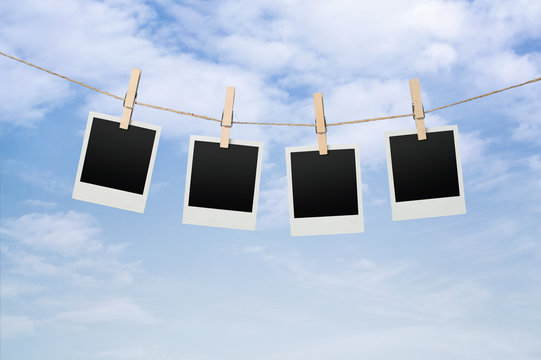 Blank instant photos drying on the clothesline over blue sky