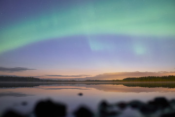 Northern lights at night above a lake in Finland at night.