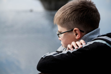 sad boy looking at the river
