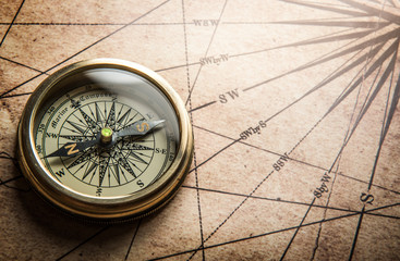 Old compass on vintage map. Retro stale.