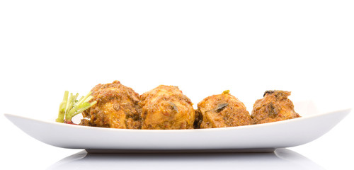 Malaysian dish Rendang Ayam or dry curry chicken in a white plate over white background