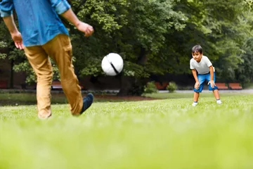 Foto op Canvas A man and a boy playing football in the park © puhhha