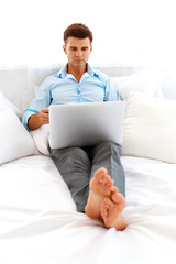 Man lying in bed with his laptop