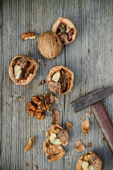 cracked walnuts and hammer on old wooden background