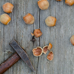 cracked nuts and hammer on old wooden background