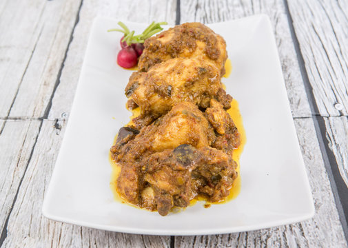 Malaysian dish Rendang Ayam or dry curry chicken in a white plate over wooden background