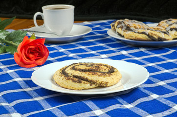 Homemade cake with poppy seeds in the shape of a snail with a cup of coffee, red rose