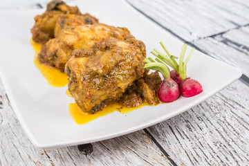 Malaysian dish Rendang Ayam or dry curry chicken in a white plate over wooden background