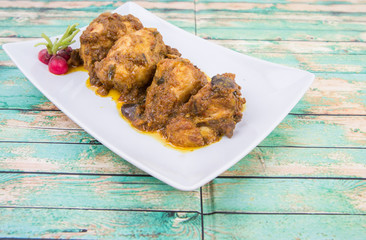 Malaysian dish Rendang Ayam or dry curry chicken in a white plate over wooden background