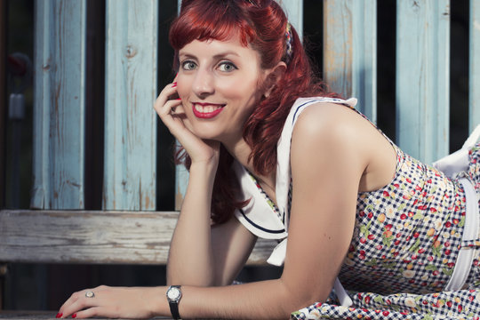 View of pinup young woman in vintage style clothing on a playground.