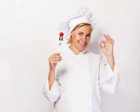 Woman chef showing a sign perfect, with tomato on fork, over whi