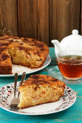 Homemade yummy apple pie, black tea in glass cup and white teapo