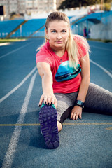 Sports woman athlete stretching her body at stadium track