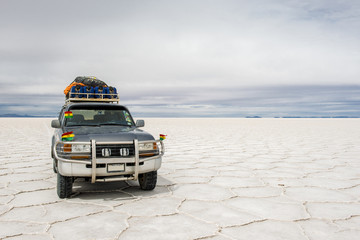 In the Salt Desert of Uyuni, in Bolivia, an off-road car with little flags of Bolivia, stay in the...
