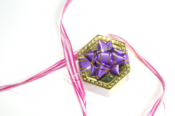 Nice golden gift box with a lilac bow and a decorative ribbon around pink. 