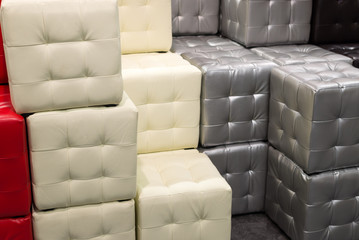 Many leather footstools of different colors in  stack