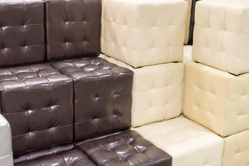 Many leather footstools of different colors in  stack