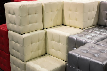 Many leather footstools of different colors in  stack