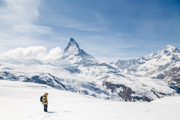 Naklejka na ściany i meble A man standing on the snow looking at the background of Matterhorn.