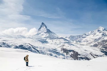 Papier Peint photo Cervin A man standing on the snow looking at the background of Matterhorn.