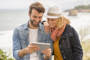 young couple using a digital tablet at seaside town