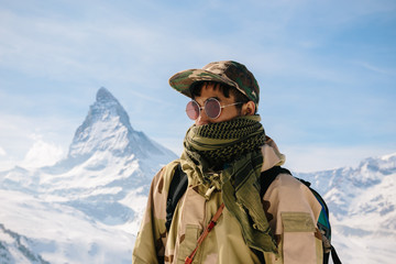 A man in camouflage winter coat standing in front of the background of Matterhorn.