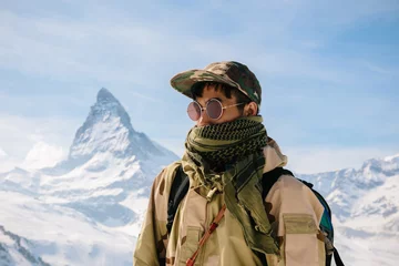 Papier Peint photo Cervin A man in camouflage winter coat standing in front of the background of Matterhorn.