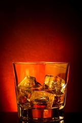 glass of whiskey on black table with reflection, red tint atmosphere