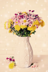 Beautiful flowers in vase on table on light background