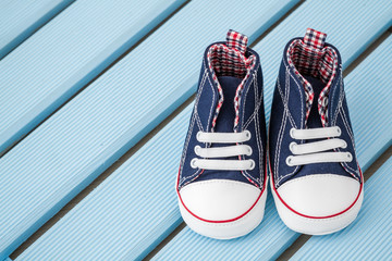 Pair of Dark Blue and White Baby Sneakers on Blue Wooden Background