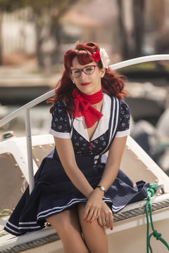 View of pinup young woman in vintage style clothing on a marina.