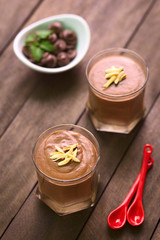 French dessert called Mousse au Chocolat, made of melted chocolate, egg, cream and sugar (Selective Focus, Focus on the front of the almond pieces on the first dessert)