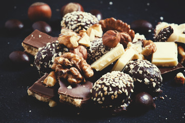 Chocolates, sweets, hazelnuts and walnuts on a dark background,