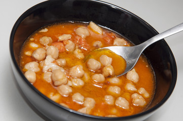 Bowl with spanish cocido. Typical iberian food made with chickpeas, sausage, potatoes, carrots and bacon.