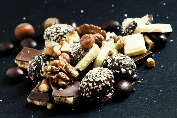 Chocolates, sweets, hazelnuts and walnuts on a dark background,