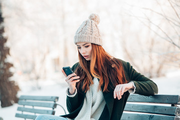 Young  woman smiling with smart phone and winter landscape .